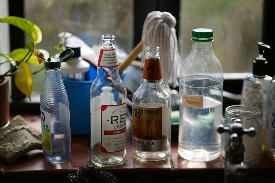 assortment of bottles containing vinegar solutions for a variety of cleaning with mop in background