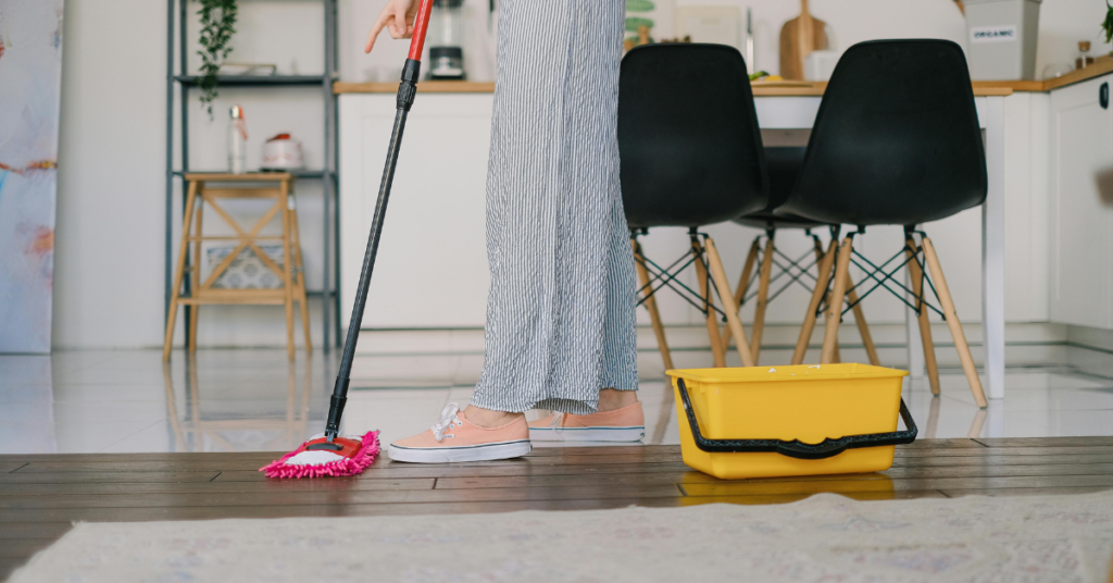 A microfiber mob is being used on a dining room wood floor with a bucket nearby
