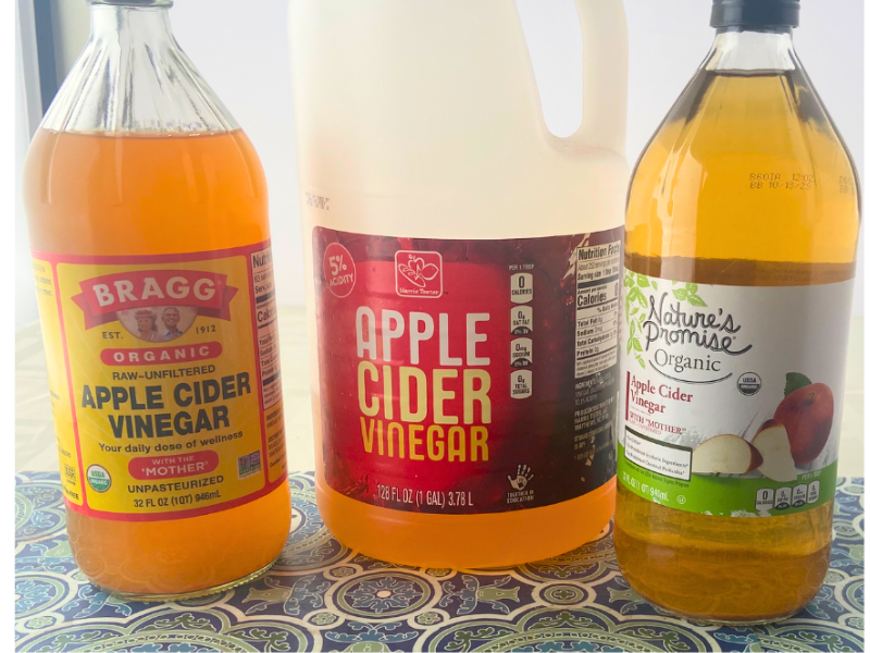 Bottle of Bragg organic apple cider vinegar, jug of Harris Teeter apple cider vinegar and Nature's Promise Organic apple cider vinegar