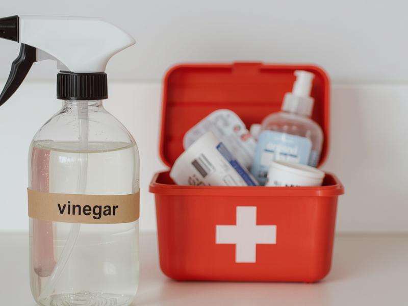 Vinegar for Bee Stings and Bites: Does It Really Help? vinegar bottle beside basic first aid supplies on counter.