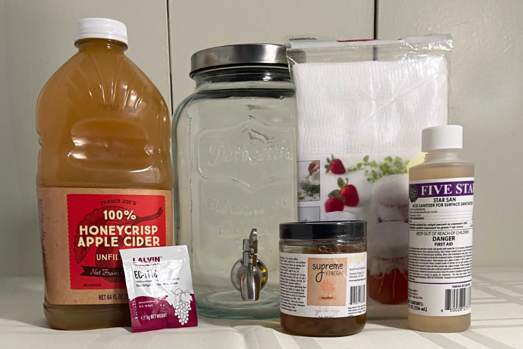 Bottle of unfiltered honeycrisp apple cider, a yeast packet, jar of apple cider vinegar 
