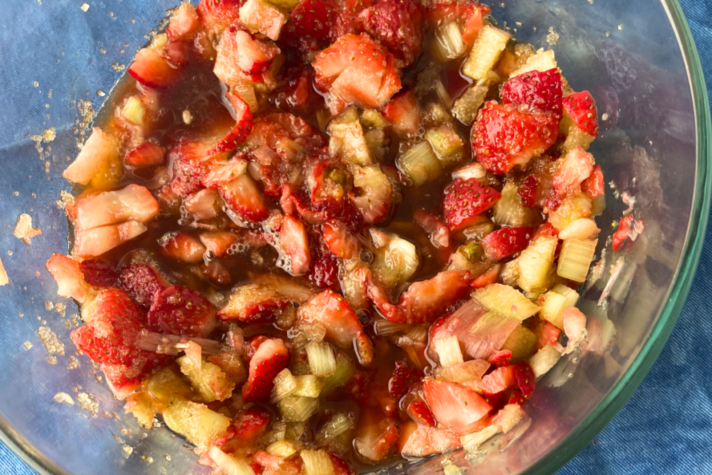 Overhead shot of mottled strawberry rhubarb shrub ingredients in a bowl