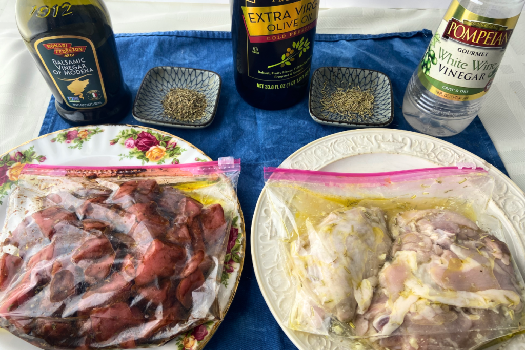 Marinating beef cubes and marinating chicken thighs in bags with balsamic vinegar, olive oil, white wine vinegar, and spices next to them.