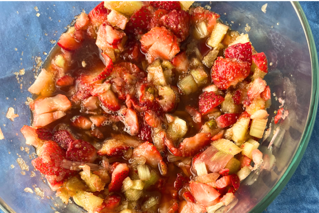 Overhead shot of macerating strawberry, rhubarb and sugar in glass bowl