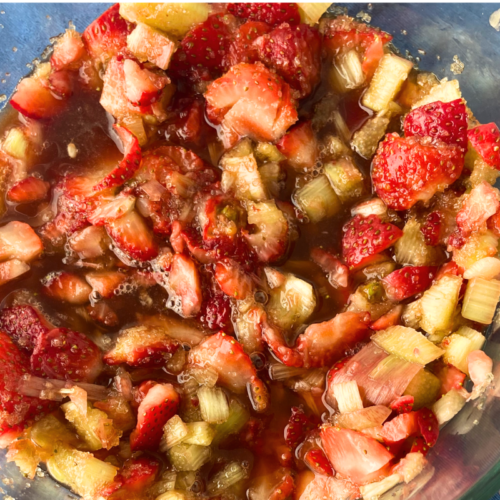 Overhead shot of macerating strawberry, rhubarb and sugar in glass bowl