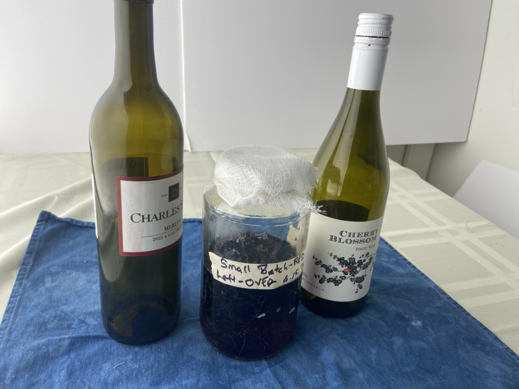 Two bottles of different wine that are making up a small batch of wine getting losing sulfites while exposed to air through cheesecloth