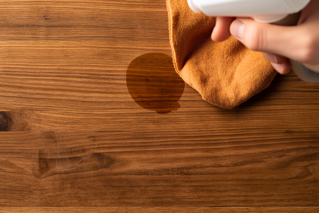 close up of a cloth about to blot at a stain on a table top