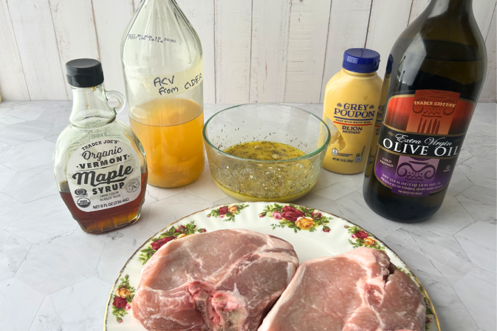 Ingredients for apple cider vinegar-maple mustard marinade, marinade in bowl and pork chops on plate before marinating.