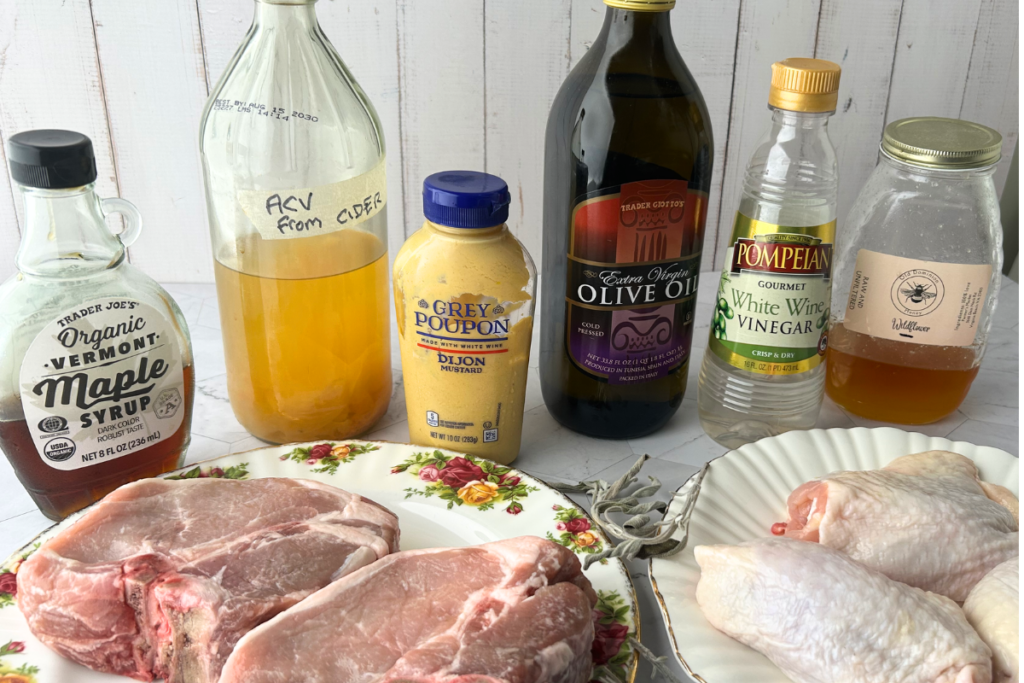 Autumn vinegar marinade ingredients with raw pork chops and raw chicken thighs ready to be marinated