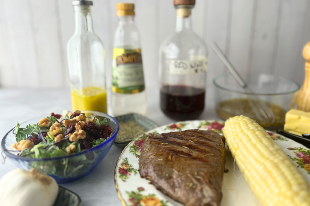 Marinated grilled steak with corn on the cob and a salad with vinaigrette for tailgating